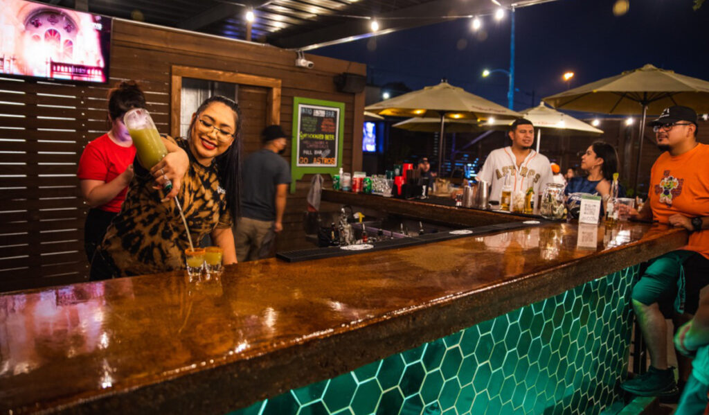 A bartender pours a drink for patrons at a bar