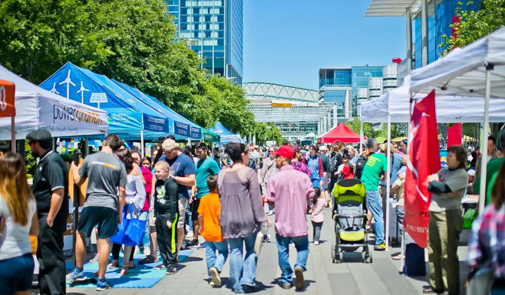 A bustling market scene with people moving past booths