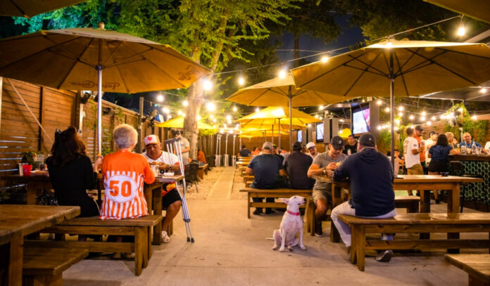 A bar patio at night with strings of lights and patrons sitting at tables