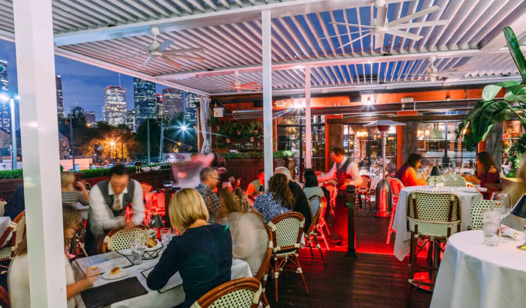 Os clientes comem no pátio superior do restaurante com vista para o horizonte do centro da cidade