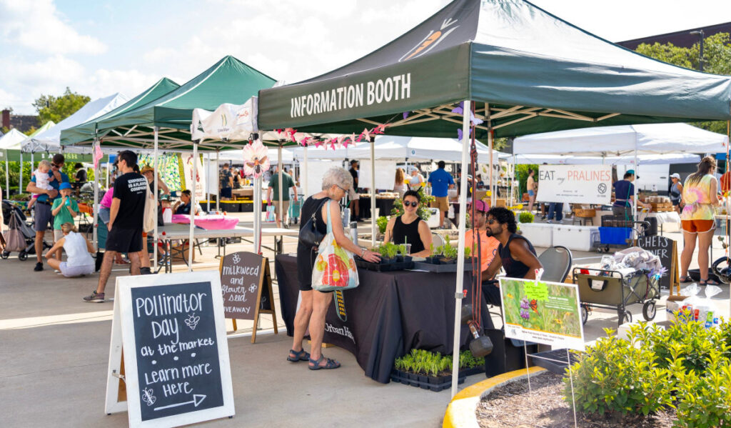 A person talks with volunteers at a market information booth