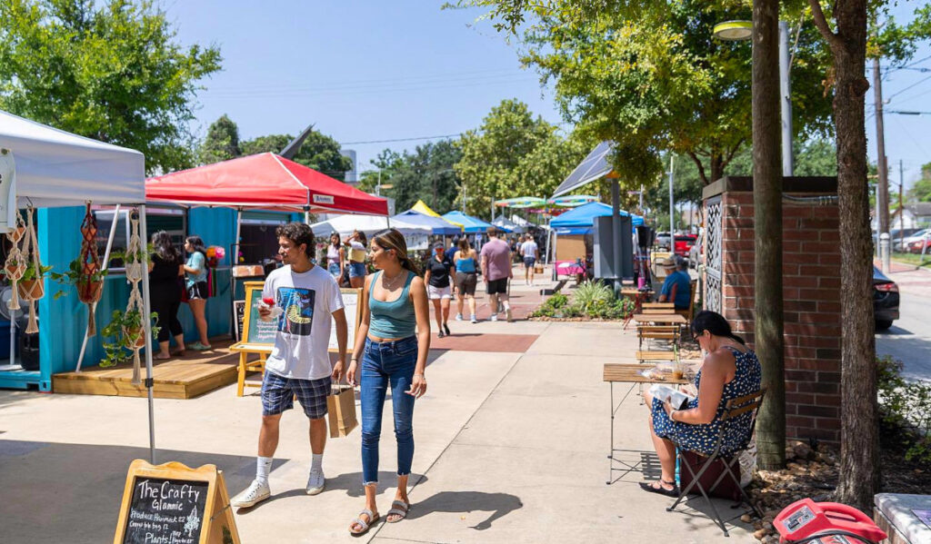 A sunny market with people walking among booths