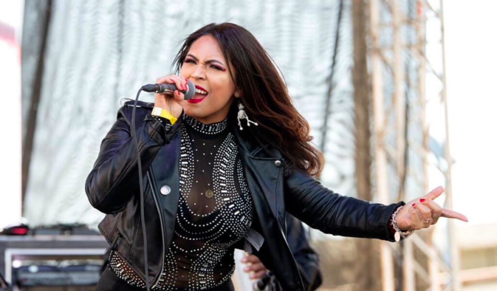 A performer dressed as Selena sings into a microphone