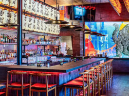 A bar interior with Godzilla mural and hanging lanterns