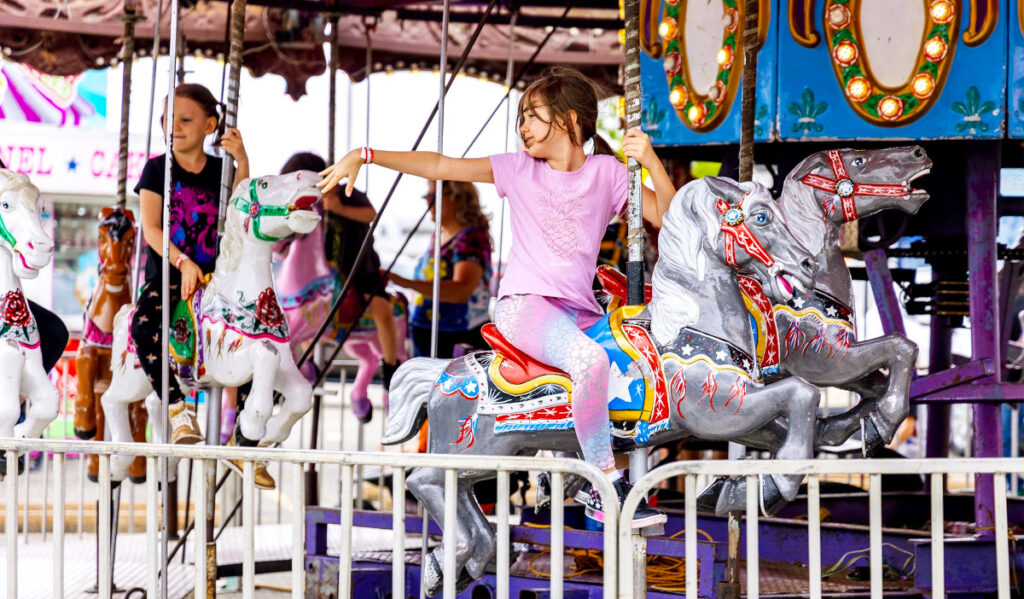 A girl looks behind her as she rides a horse on a carousel