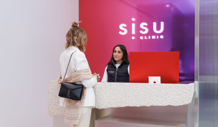 A visitor speaks with a staff member at the Sisu Clinic desk