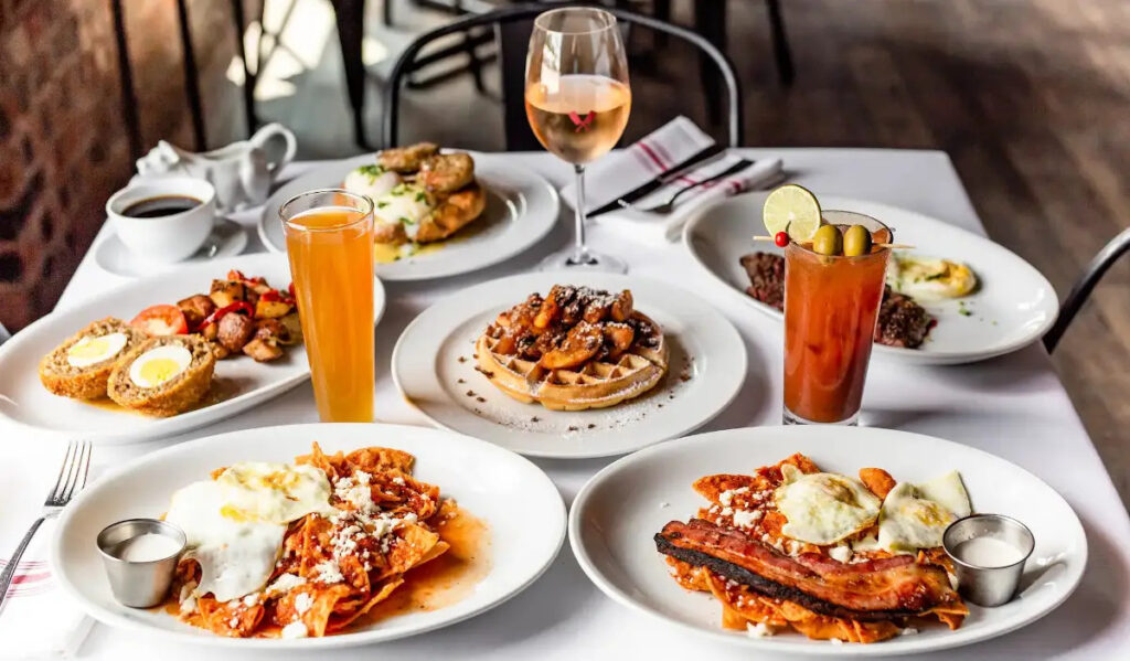 A spread of dishes like chicken and waffles omelettes, and other brunch meals