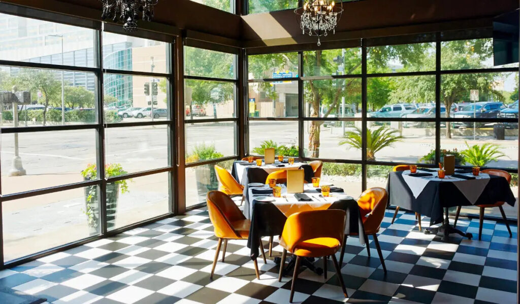 A table in a sunlit corner of a restaurant with windows that view onto Downtown streets