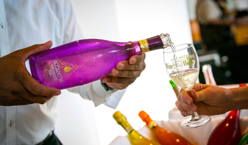 A person's hands pouring a glass of wine for another person