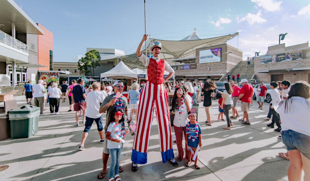 A roaming entertainer on stilts poses with a family for a photograph