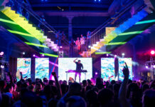 Things to Do for Pride Weekend in Houston A DJ performs to a crowd with rainbow lights behind him
