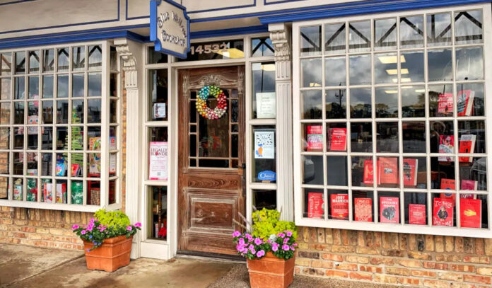 The exterior of Blue Willow Bookshop with flowering plants outside and books in the shop window