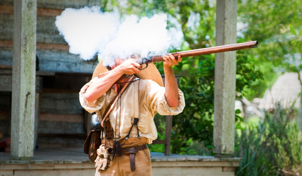 A person in historical clothing fires a musket