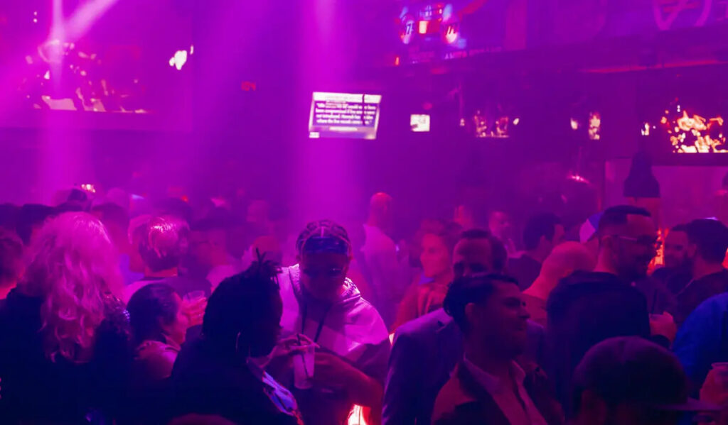 A nightclub scene with dancers in purple light