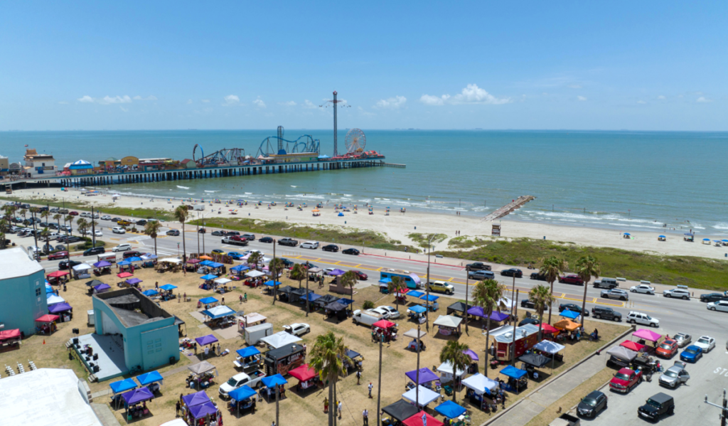 An aerial view of a marketplace on the shores of Galveston with an amusement park in the background