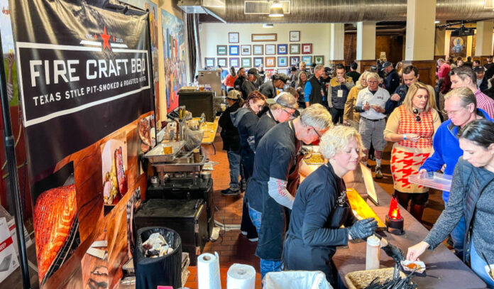 An indoor food festival with people sampling from bbq vendors