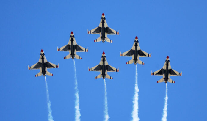 Six Air Force Thunderbirds fly overhead with trails behind them