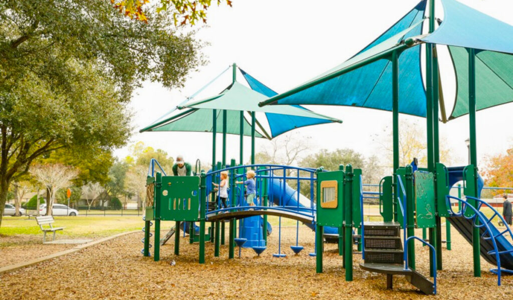 Young children play on playground equipment in a park