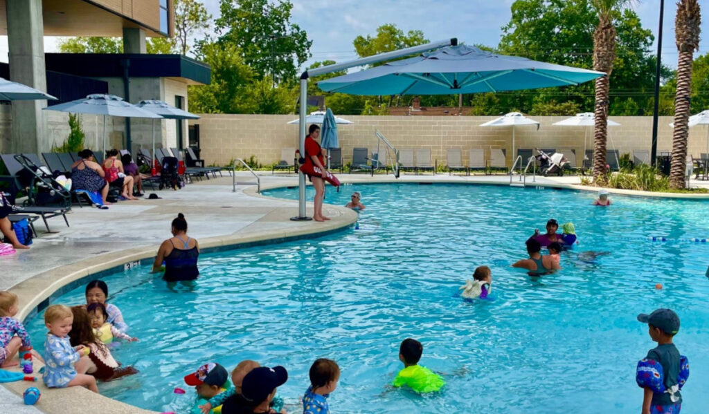 Children swimming in a pool as a Lifeguard looks over them