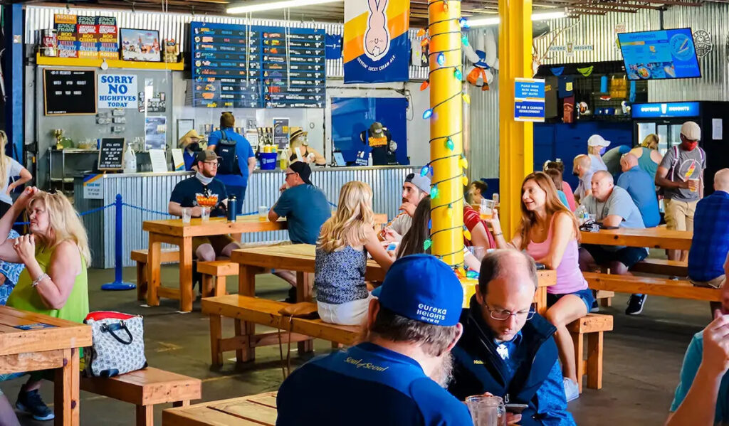 Interior of a brewery taproom with patrons at tables drinking and covnersing