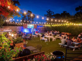 An outdoor patio space at night with a string of lights overhead