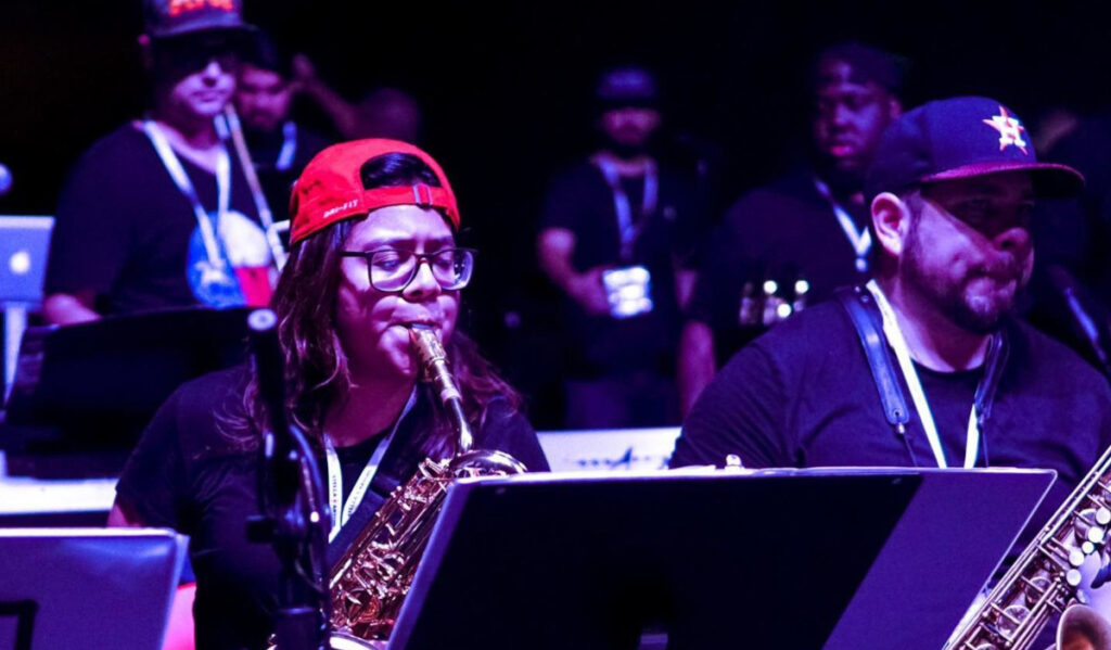 Musicians play brass instruments while wearing Houston sports baseball caps