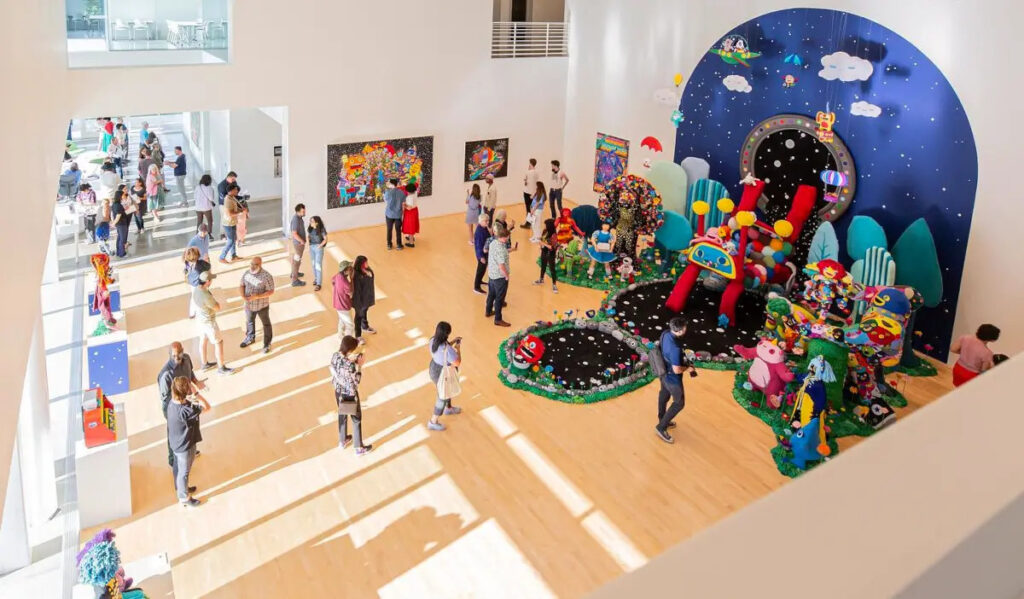 The Moody Center for the Arts gallery space with a colorful installation in place and people walking around it