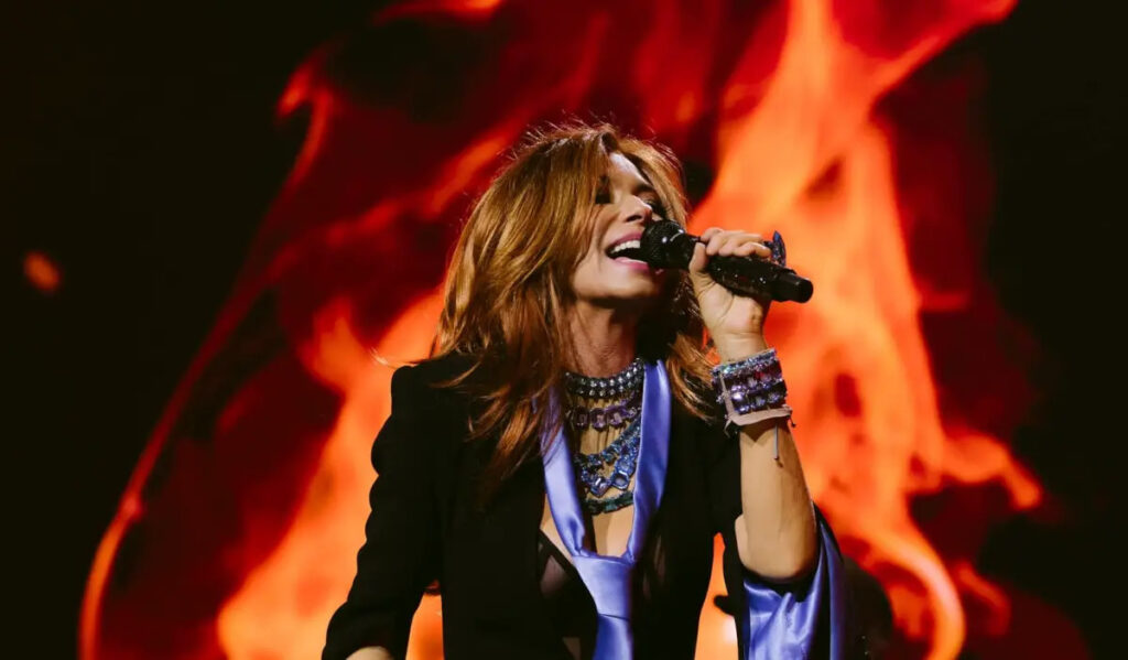 Shania Twain performs with an image of fire behind her