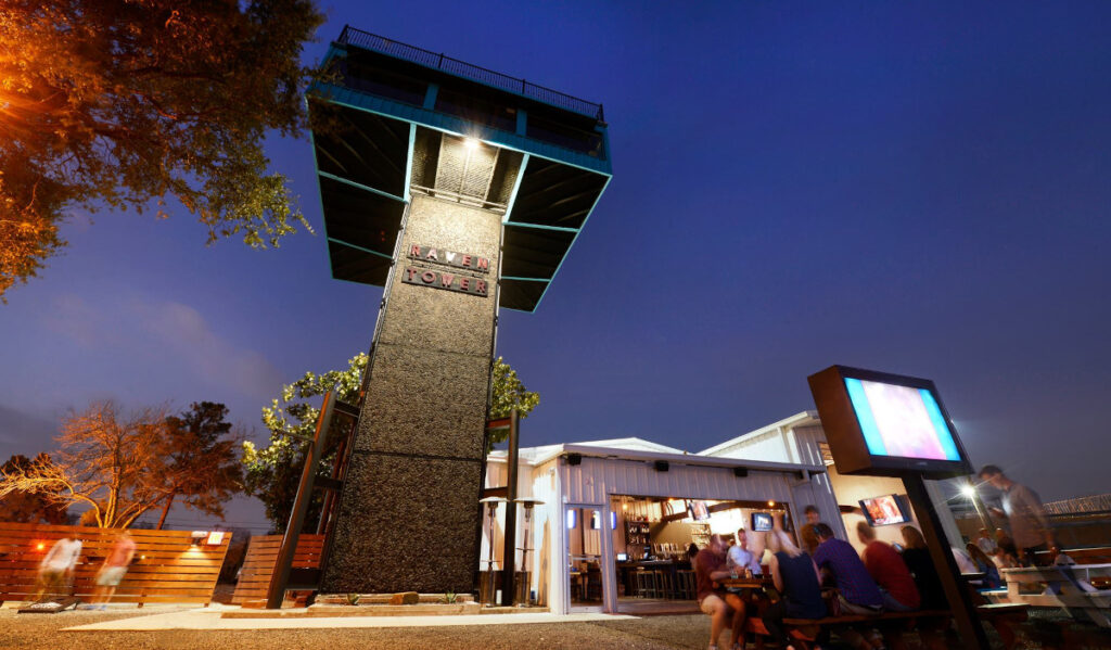 An exterior image of Raven Tower with people sat at a picnic table below it