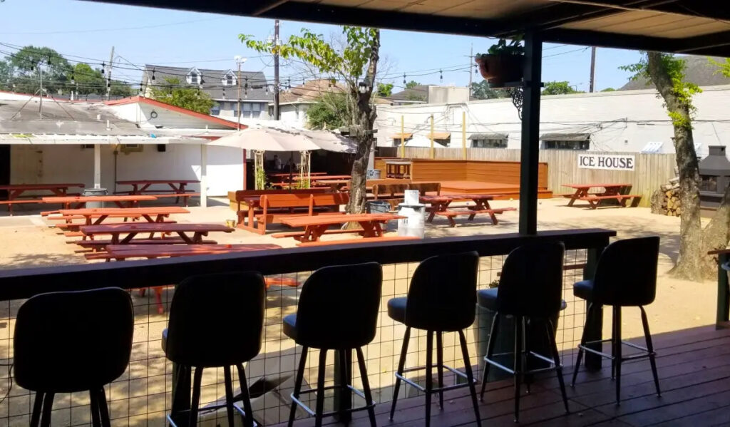 An outdoor patio with red picnic tables and a covered row of seating