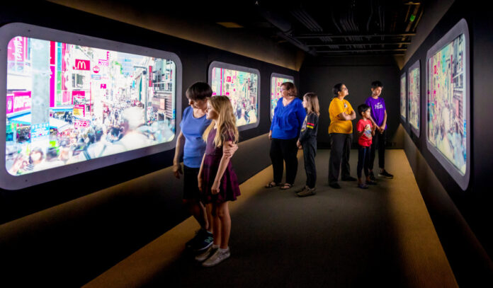 Visitors stand within a virtual bullet train and watch videos through the windows