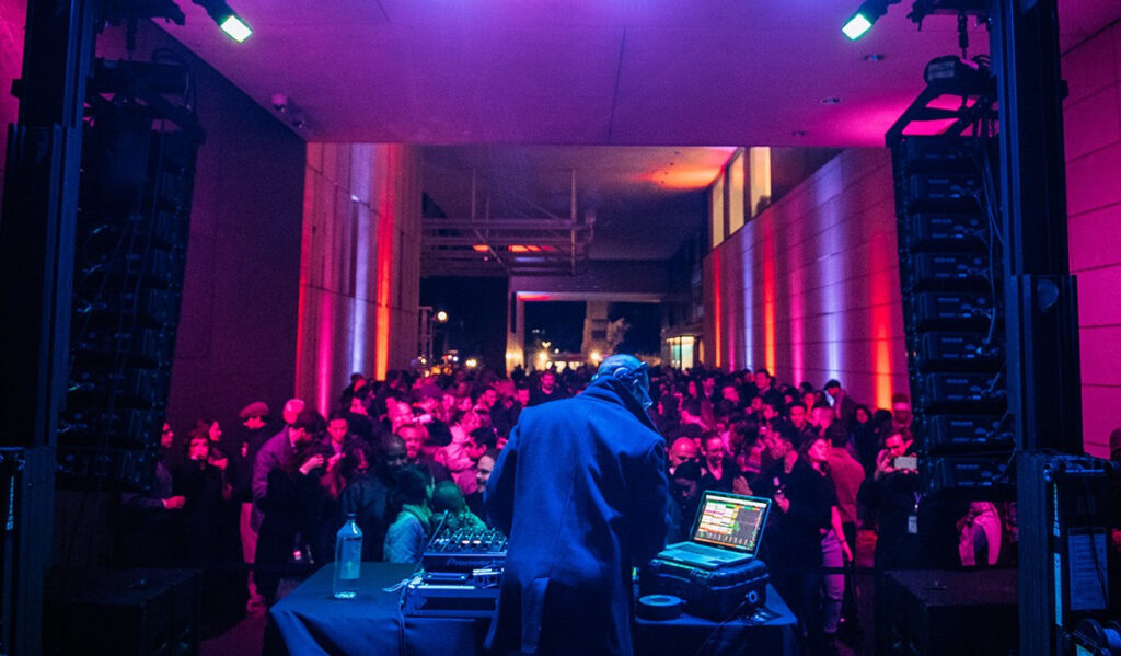 A crowd of people dancing while a DJ performs 