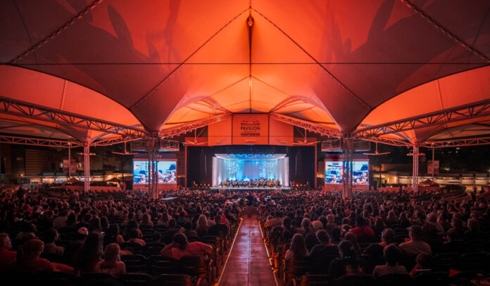 A view of Cynthia Woods stage from under a red-lit canopy