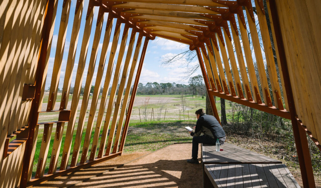 A person reading a book while in a bird blind facing the Memorial Park prairie