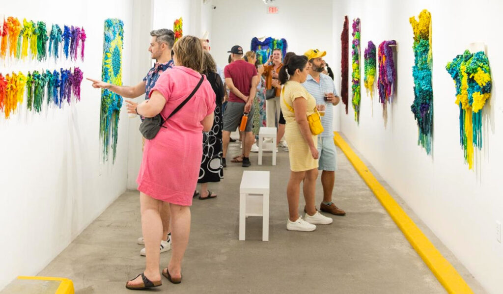 People in a hallway looking at colorful hanging artwork