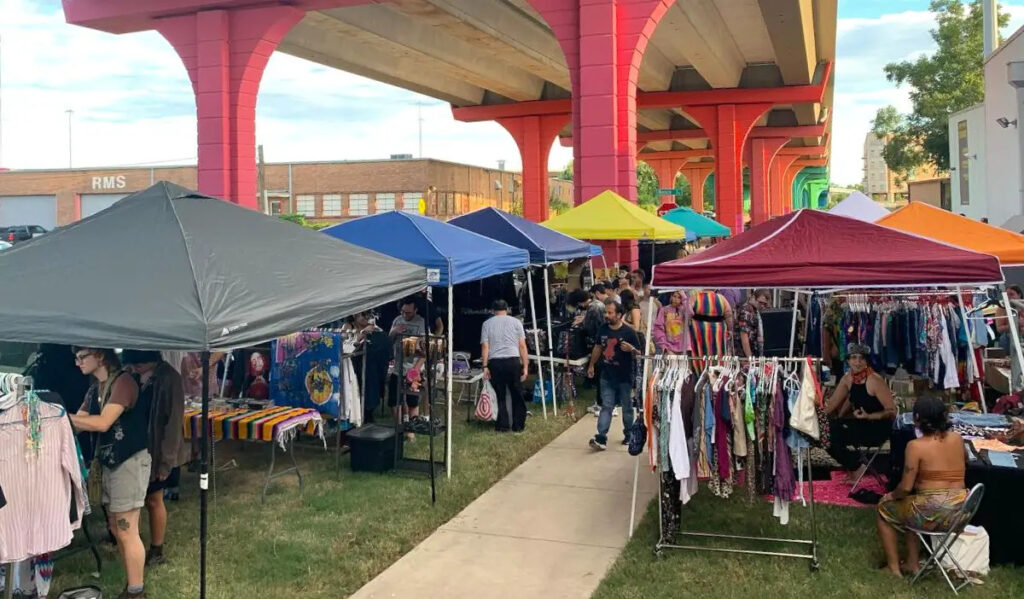 An outdoor market of local vendors with colorful structures overhead