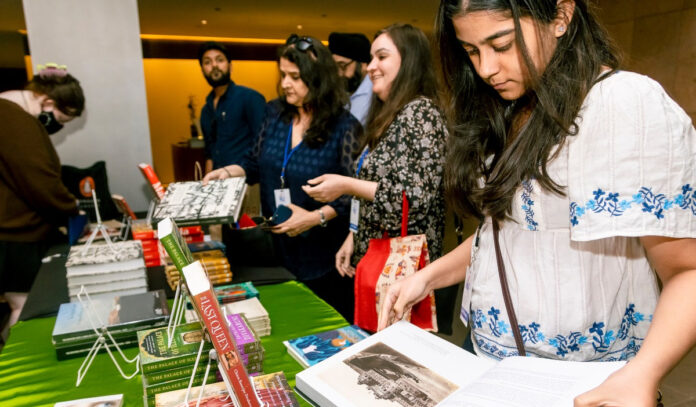 People standing in line at a book booth, looking through a book