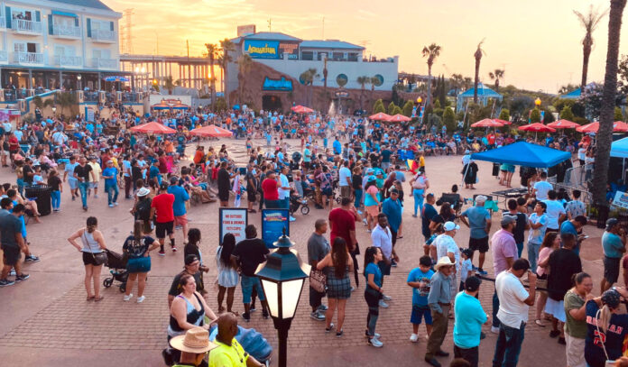 The plaza of Kemah Boardwalk with families and groups of people gathered for music