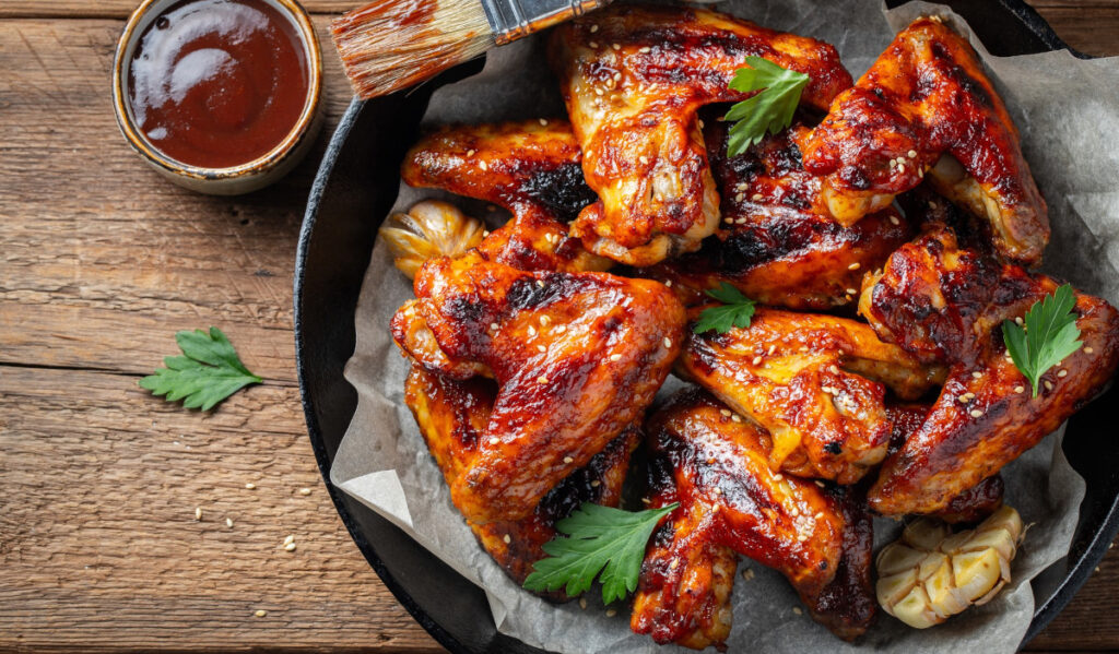 A pile of sauced chicken wings in a cast iron skillet