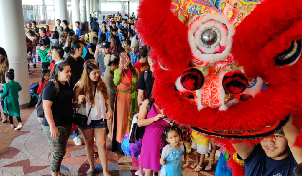 A gathering of people watch as a person performs a dragon dance