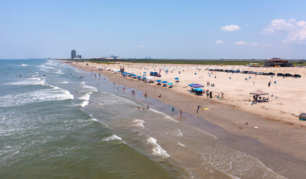 An aerial view looking toward the coast of Galveston with waves rolling in