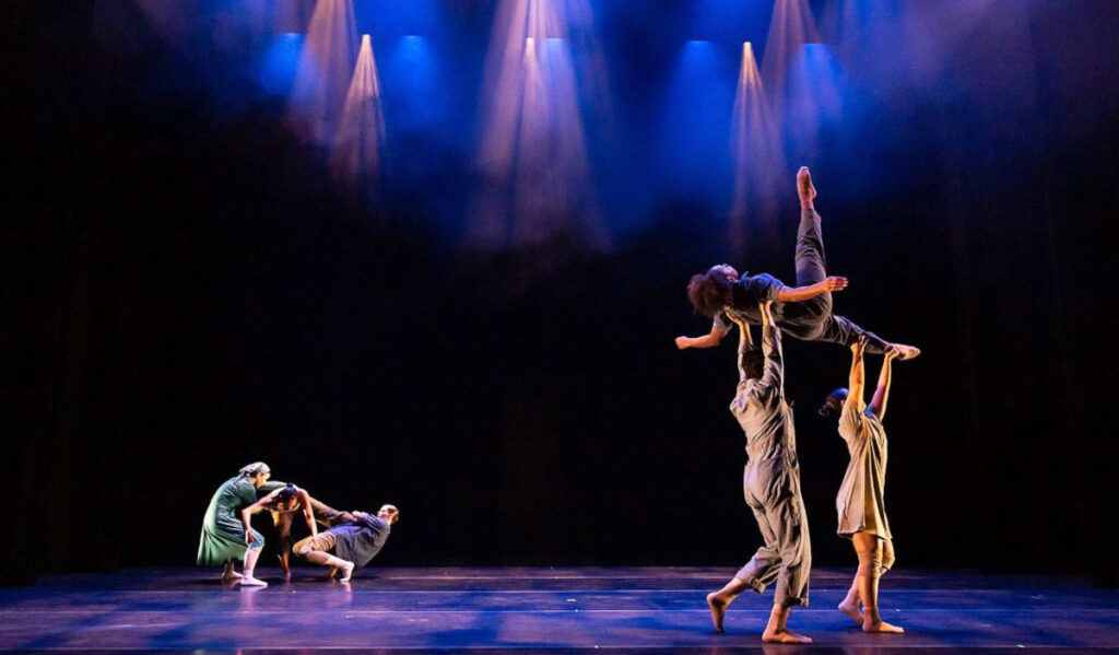 A company of dancers performs a contemporary routine on stage