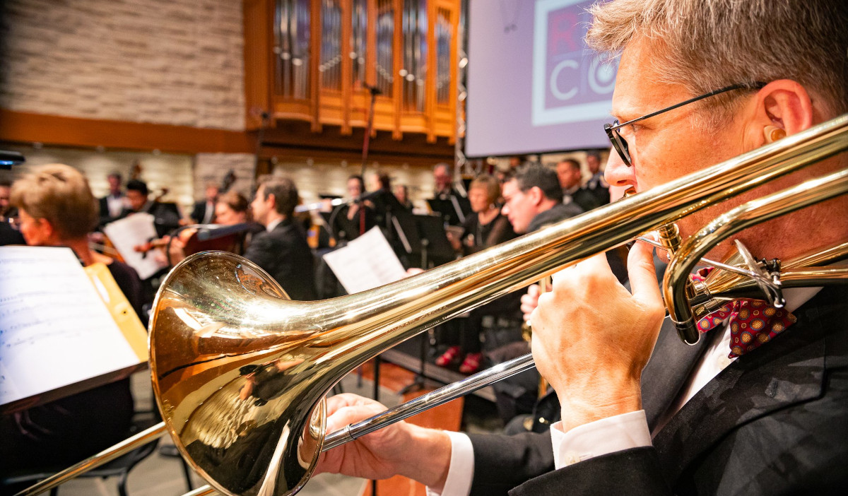 A close up of a trombonist performing from sheet music