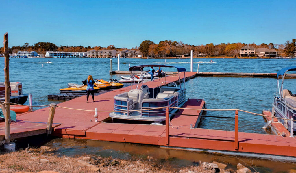 People walking along a dock next to boats and jet skis