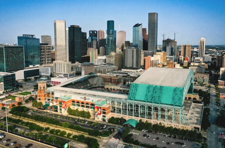 An aerial view of Minute Maid Park with the roof open and Downtown skyscrapers in the background
