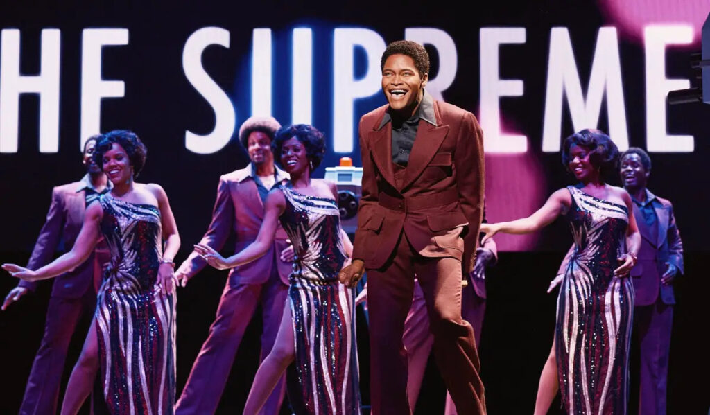 A promotional image of a singer performing in the Broadway production 'Ain't Too Proud'