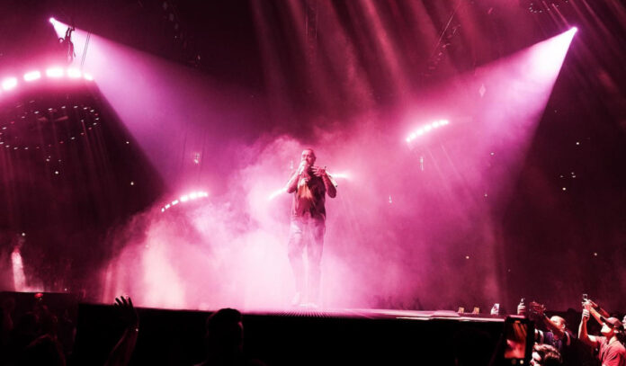 Post Malone performing on stage while pink spotlights shine on him