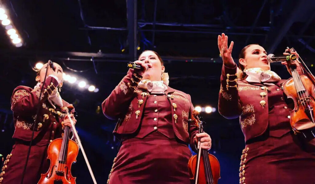 Three mariachi performers sing