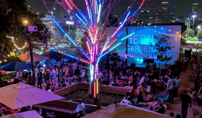 The bustling outdoor patio at Axelrad with a neon-lit tree and "Neon Garden" projected on the wall