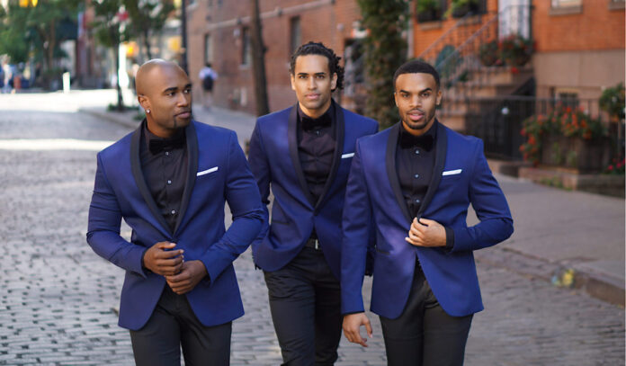 Three members of Uptown in blue suits pose while walking down a New York street